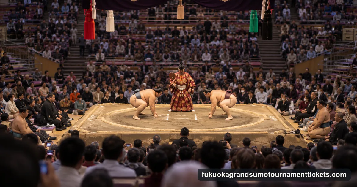 Two sumo wrestlers crouched at the starting lines facing each other while the referee holds his fan between them